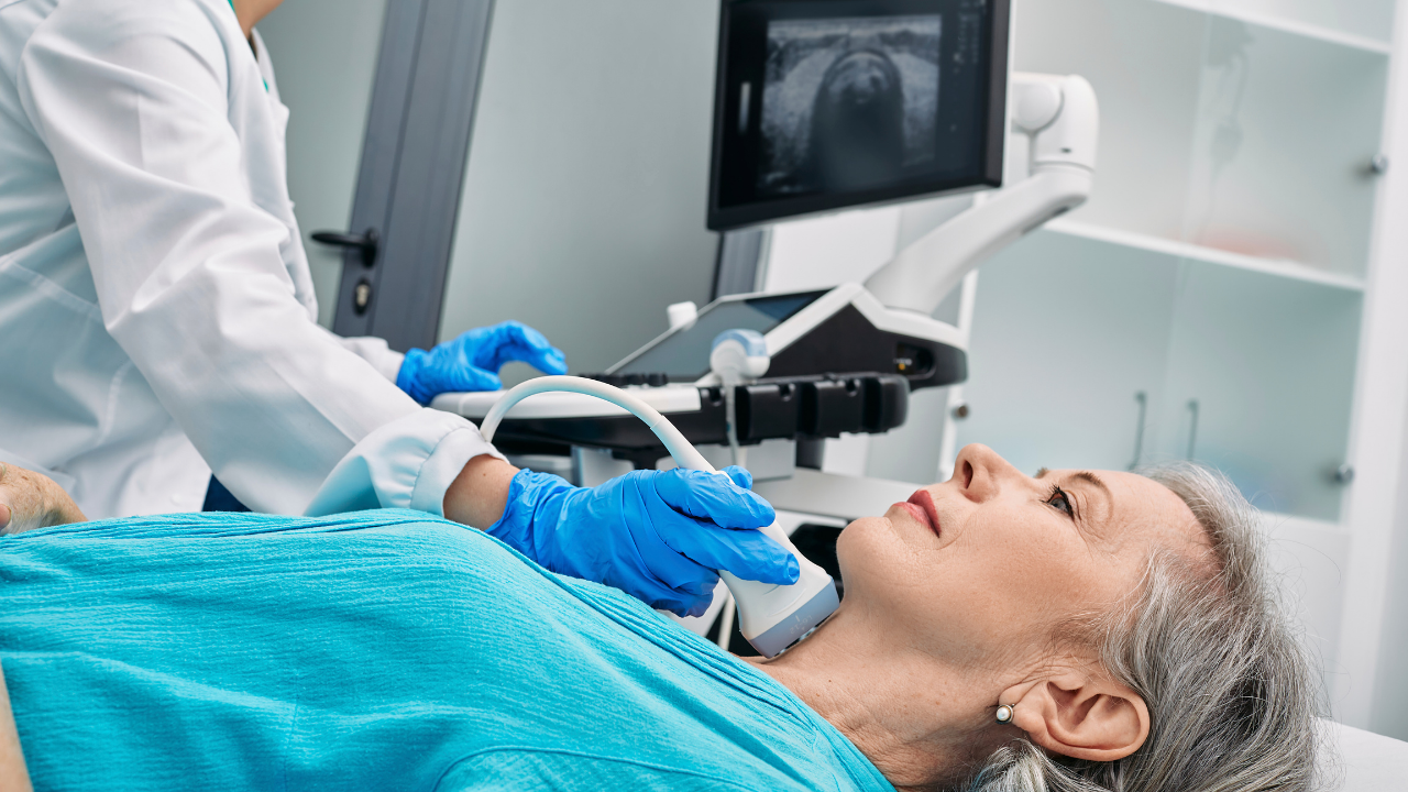 A doctor conducts a thyroid ultrasound scan on an older female patient. Photo by PEAKSTOCK of Science Photo Library, sourced from Canva.